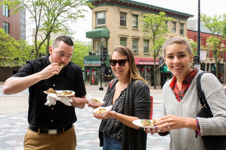 Three people eating food on State Street.