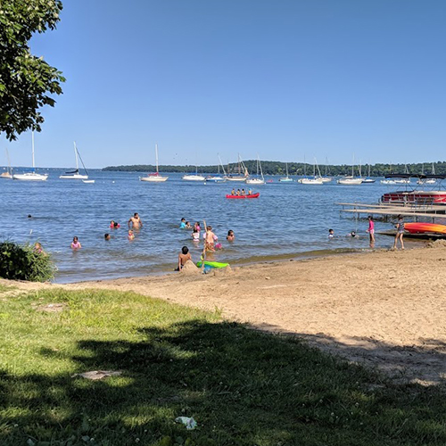 Beach with people, there are boats in the distance.