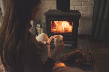 Person sitting in front of a fireplace.