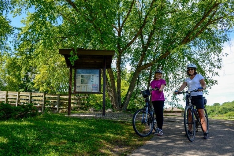 Two people standing with bicycles on a path.