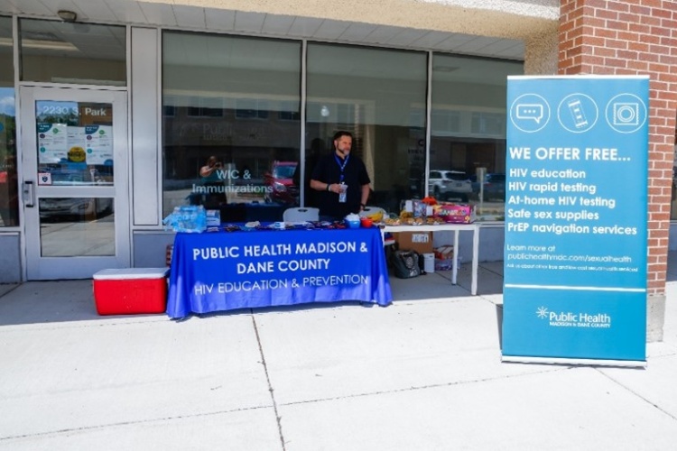 A person standing behind a table offering HIV education and prevention.