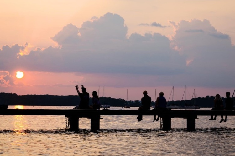 Silhouettes of people sitting on a pier at sunset.