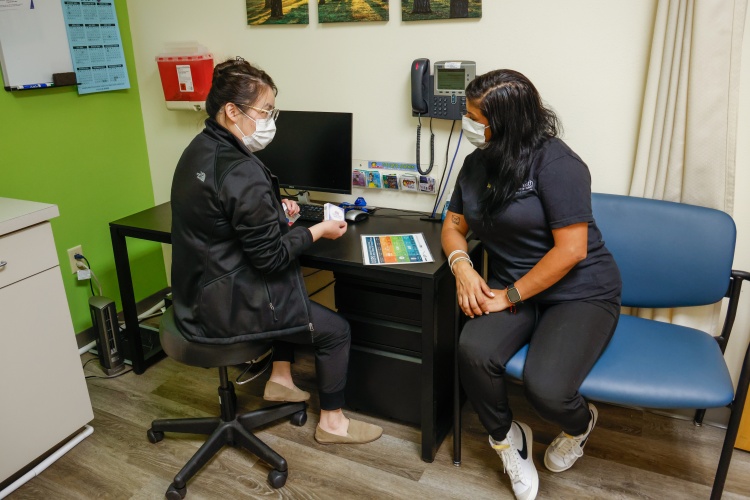 A Public Health worker wearing a mask talking to a patient wearing a mask.