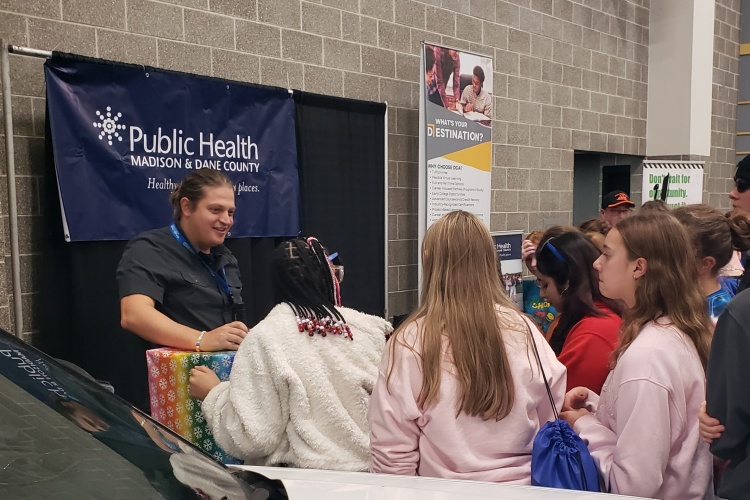A Public Health worker talking to teenagers at an event.