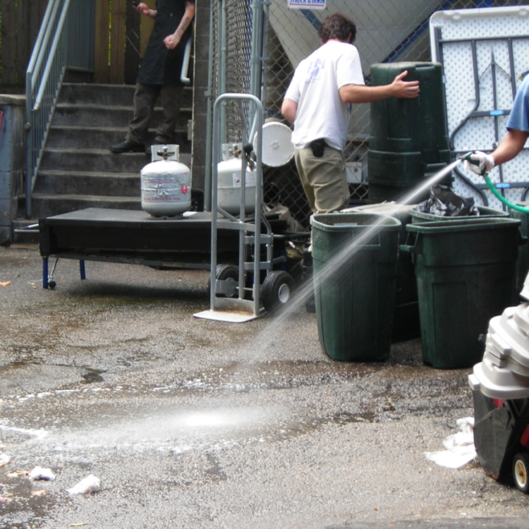 Using a hose to spray waste into a gutter.