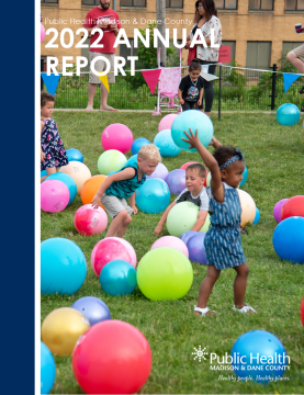 2022 Annual report cover has children playing outside with large blow up balls