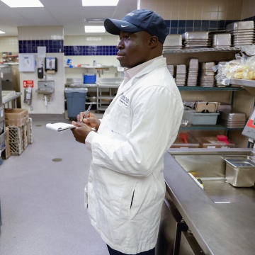 Public Health staff inspecting a restaurant kitchen, holding paper and pen.