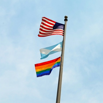 American, Madison, and LGBTQ flags on a pole