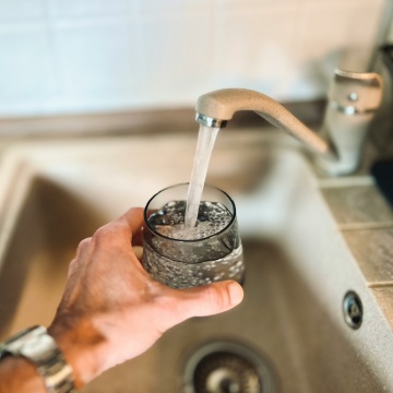 Person filling a cup of water at the faucet.