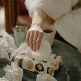 A person reaches for a tissue from bed