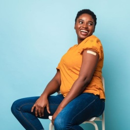 a person is sitting on a chair and smling away from camera with a bandaid on their arm